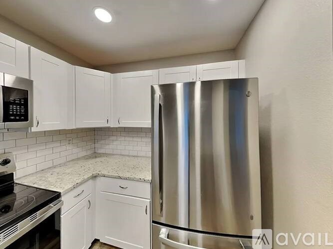 A kitchen with a stainless steel refrigerator and white cabinets.