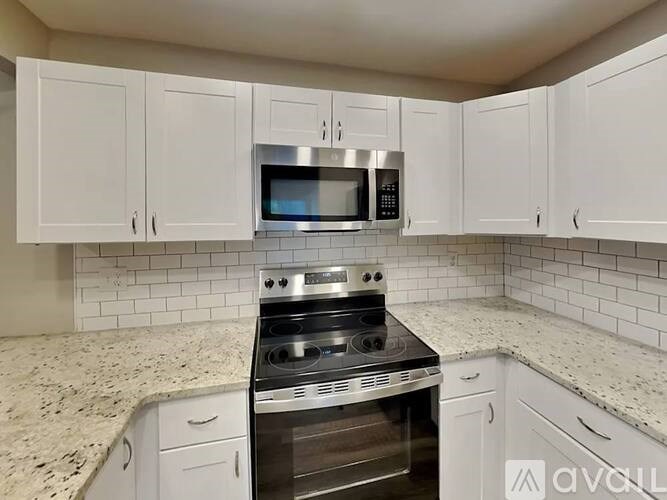 A kitchen with white cabinets and a stainless steel stove top oven.