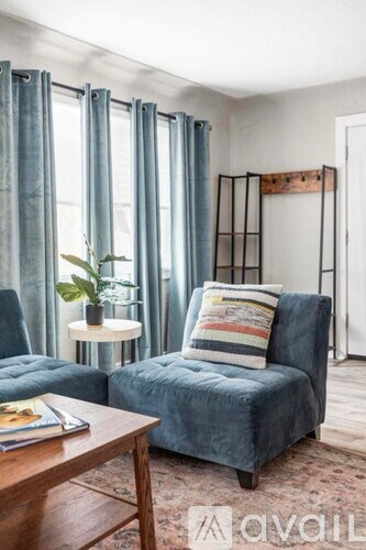 A living room with a blue chair and a small table with a plant on it.