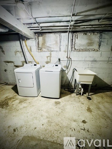 Two white appliances in a dirty basement.