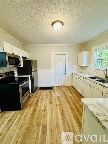 A kitchen with wooden floors and white cabinets.