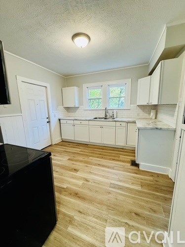 A kitchen with white cabinets and a black fridge.