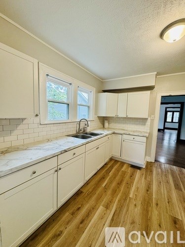 A kitchen with white cabinets and a marble countertop.