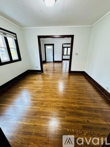 A room with wooden flooring and a doorway leading to another room.