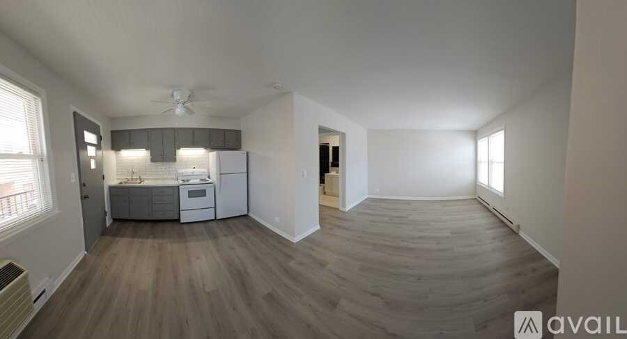 A spacious living room with a kitchen in the background and a hardwood floor.