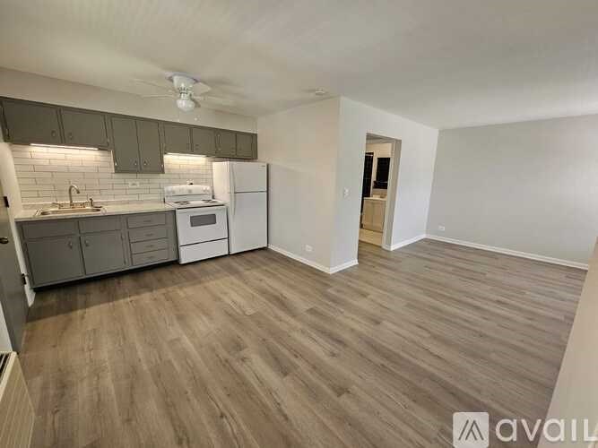 A kitchen with a white fridge and a wooden floor.