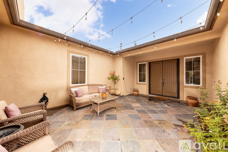 A patio with a couch, chairs, and a table with a vase of flowers on it.