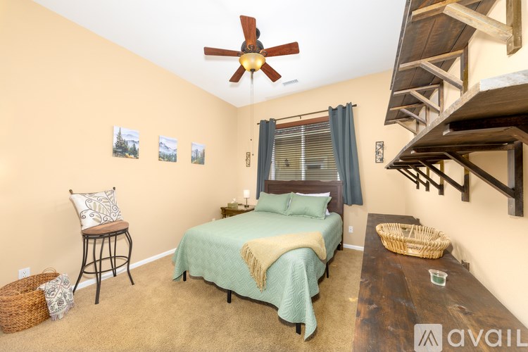 A bedroom with a bed, chair, and pictures on the wall.