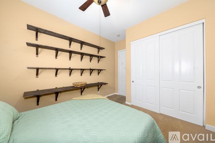 A bedroom with a bed, shelves, and a ceiling fan.
