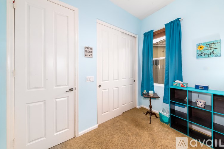 A room with two doors and a shelf with a painting on it.