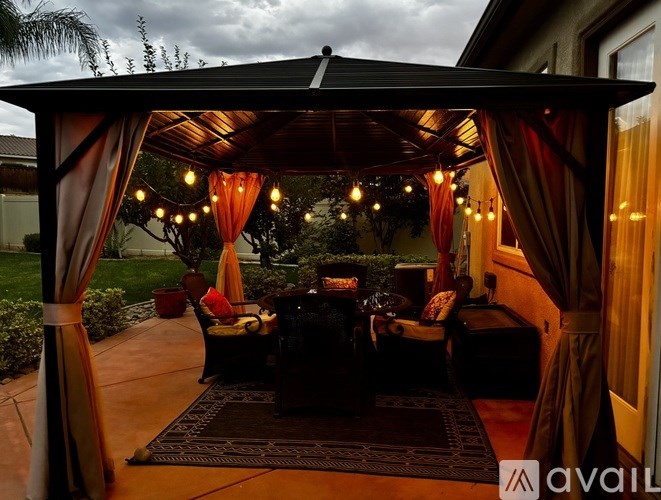 A cozy outdoor seating area with a canopy and string lights.