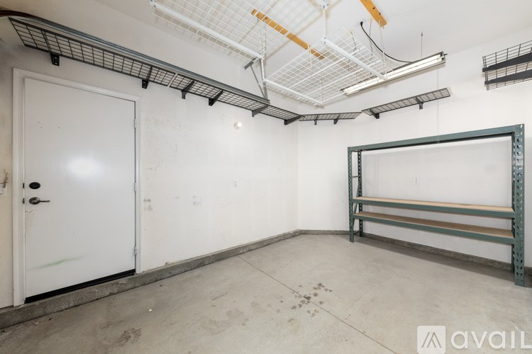 A white door is on the left side of a room with a metal shelf on the right.