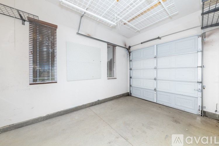 A spacious garage with a white door and a window with blinds.
