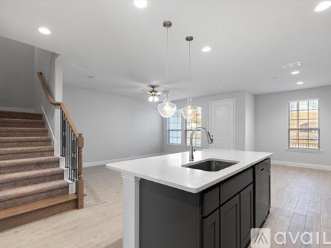 A kitchen with a sink, stairs, and a window.