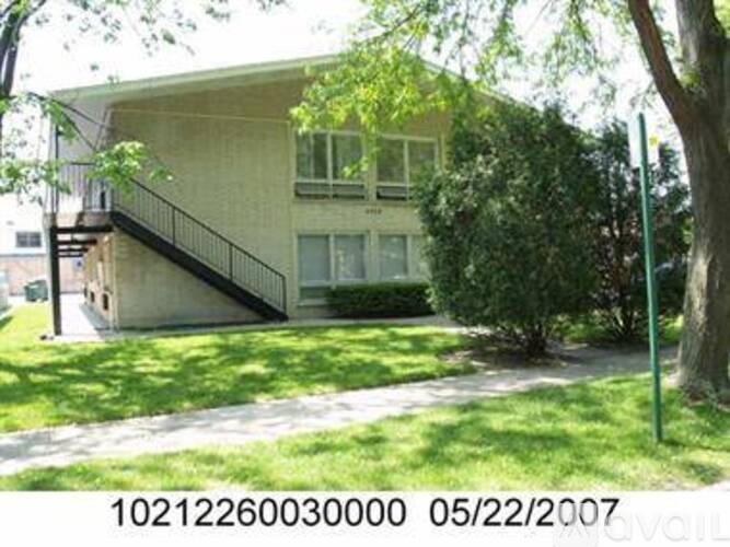 A house with a green lawn and a tree in front of it.
