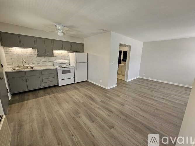 A kitchen with a white fridge and wooden floors.