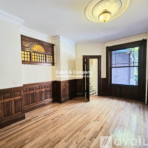 A room with wooden floors and a large window with a wooden frame.