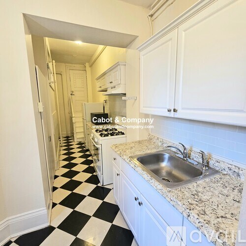 A kitchen with a checkered floor and white cabinets.