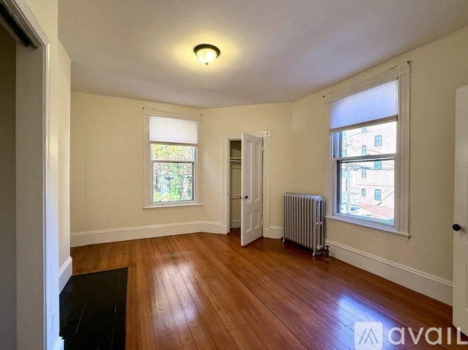 A room with wooden floors and a window with a view of a cityscape.