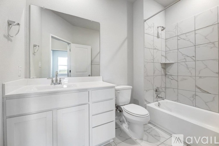 A white bathroom with a marble tile wall and a bathtub.