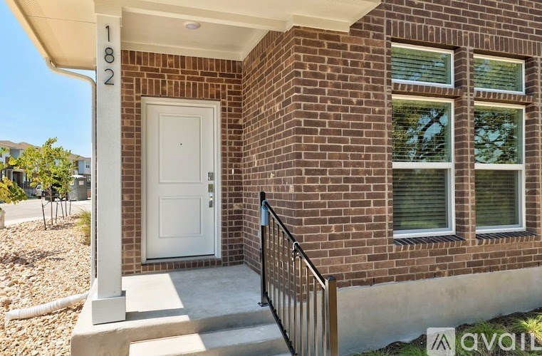 A house numbered 182 has a white door and a black railing.