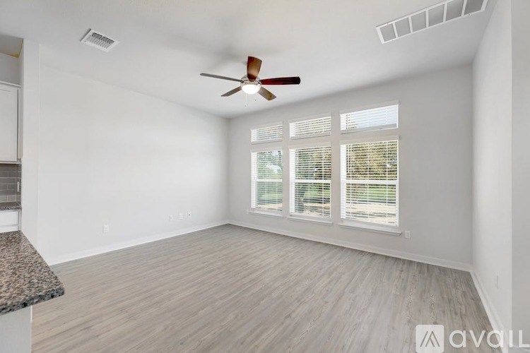 A room with a ceiling fan and a window with blinds.