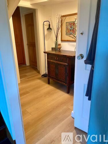 A hallway with a wooden floor and a wooden cabinet with a vase on top.