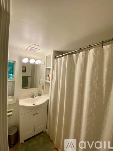A bathroom with a white shower curtain and a white sink.