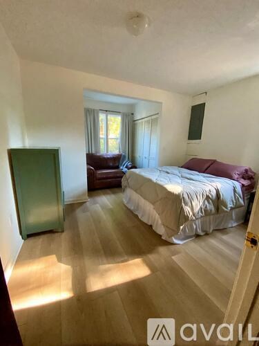 A bedroom with a bed, chair, and a green cabinet.