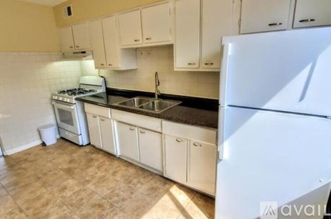 A kitchen with white cabinets and a white fridge.