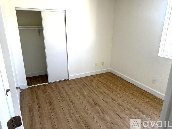 A room with a white door and wooden flooring.