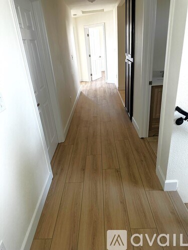 A hallway with wooden floors and white walls.