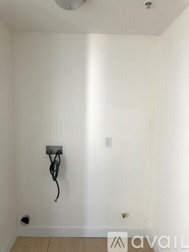 A wall socket with a black cord plugged into it.