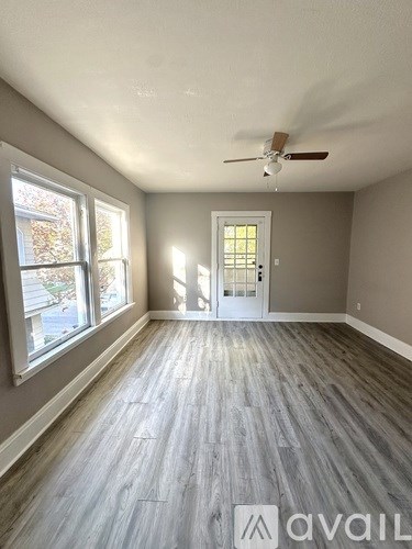 A room with a ceiling fan and a door leading to a hallway.