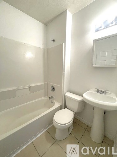 A white bathroom with a toilet, sink, and bathtub.