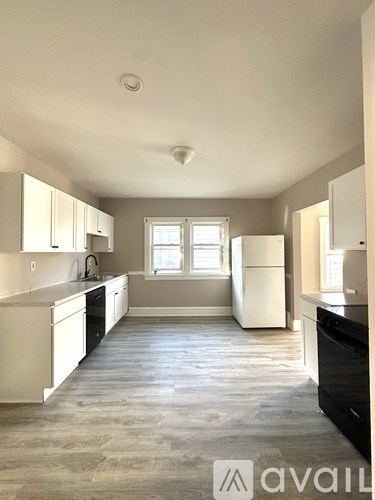 A kitchen with white cabinets and a black fridge.