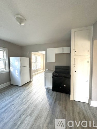 A kitchen with a white fridge, black dishwasher and white cabinets.