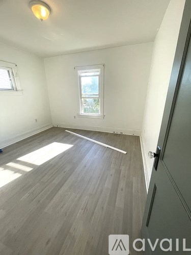 A room with wooden flooring and a window letting in sunlight.