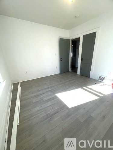 A room with a grey floor and white walls with two doors.