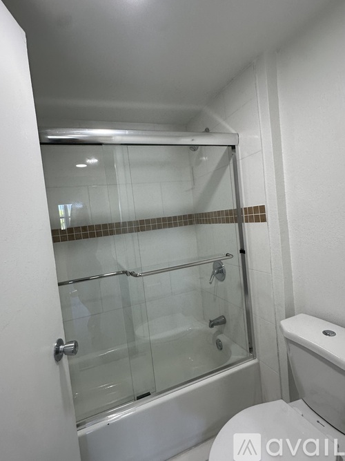 A bathroom with a glass shower door and a toilet.