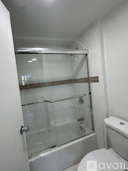 A bathroom with a glass shower door and a toilet.