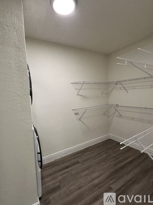 A room with a white wall and a wooden floor with a clothes rack.