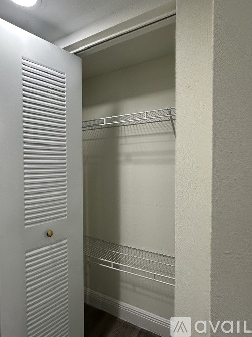 A white closet with a door and shelves.