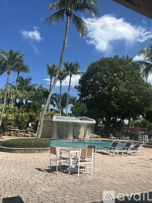 A pool surrounded by palm trees and lounge chairs.