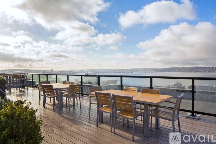 A wooden table and chairs are set up on a balcony overlooking a cityscape.