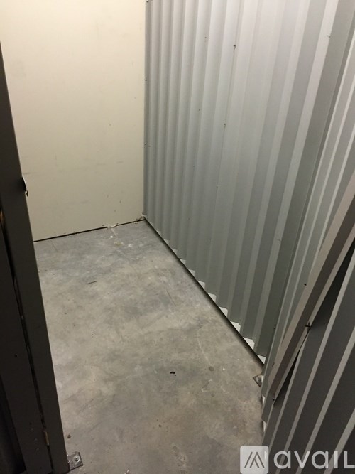A room with a grey floor and a grey wall with a metal striped panel on the right side.