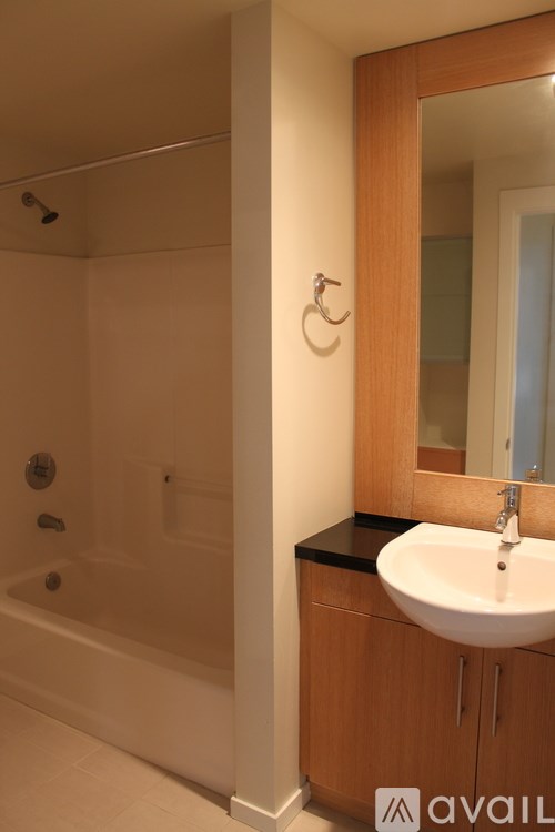 A bathroom with a sink, mirror, and bathtub.