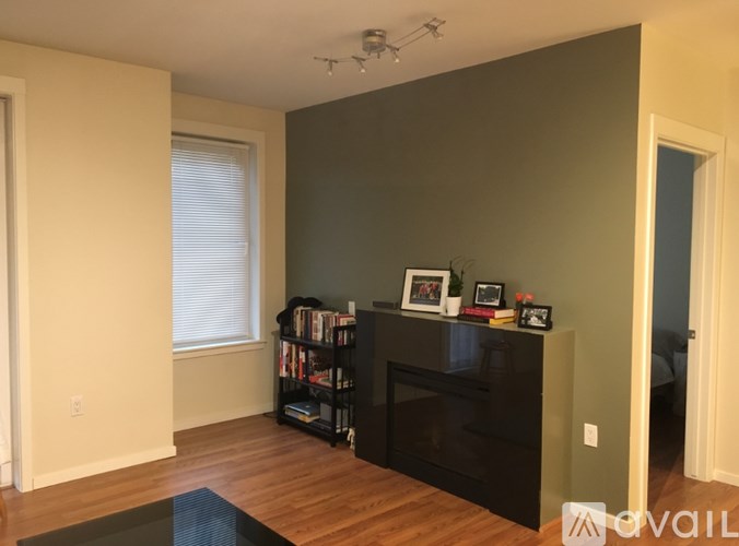 A living room with a black bookcase and a window with blinds.