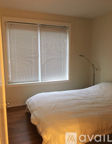 A bedroom with a bed, a window with blinds, and a lamp.