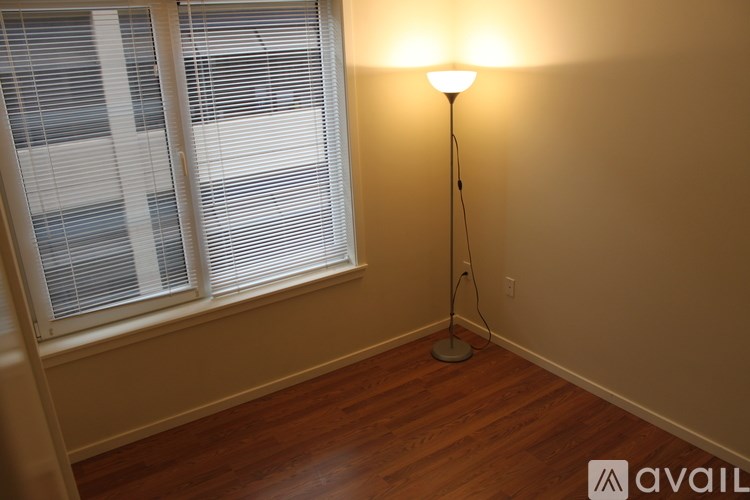 A lamp stands in a corner of a room with a window and blinds.